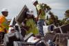 Three men unloading electronic waste from a pick-up truck. 